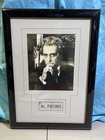 Frontal view of the framed black and white photo showing Al Pacino with his signature on the white cuff area of the photo, mounted with black frame and white matte with 'AL PACINO' text.