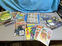 A spread of comics, trading cards and binder sheets containing cards. Shows a variety of comic titles and trading cards mainly related to X-Men and some X-Files cards.
