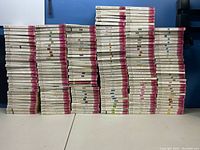 Front view of multiple stacks of Harlequin Presents romance paperbacks, showing mostly white and pink spines with various author names and series identifiers.