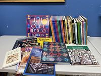 Photo showing front view of the lot with books standing and lying flat, highlighting titles related to quilting techniques and history.