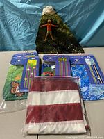 Front view of the oil on marble painting featuring a person on a rock. American flag folded in front and four packaged windsocks arranged.