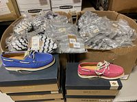 Two cardboard bins filled with individually packaged swimwear behind stacked shoeboxes topped by a blue and a pink Sperry boat shoe.