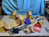 Wide shot of two large halfpipe ramps, several smaller ramps in different colors, and assorted Tech Deck figures and accessories on a table with blue backdrop