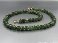 Jade beaded necklace arranged to show full strand and 14CT gold clasp with safety clasp.