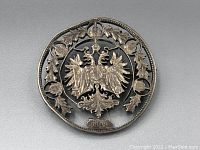 Front view of the antique pierced coin brooch showing double-headed phoenix and decorative leaves with date 1904 plaque