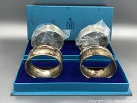 Two sets of Birks sterling silver napkin holders in blue box, one set still in plastic wrapper.