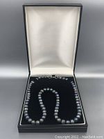 Necklace arranged in open black velvet-lined box showing full strand.