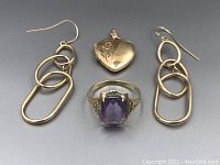 Group shot of ring, locket, and earrings on grey background