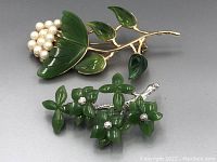 Pair of floral pins on gray background showing carved jade leaves and pearl cluster, and carved jade flowers with rhinestones