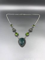 Full view of the necklace showing jade pendant center and peridot stones with silver chain.