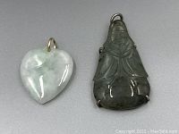 Photo of jadeite heart pendant and jadeite Buddha pendant with silver backing side by side on white background.