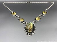 Full view of the necklace showing the chain, four round yellow citrine stones, and the central ornate labradorite stone set in sterling silver.