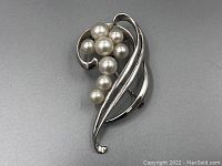 Front view of Mikimoto sterling silver brooch adorned with ten luminous pearls arranged artistically.