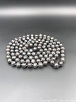 Coiled grey pearl necklace showing individual pearls, lustrous surface, and pearl size.