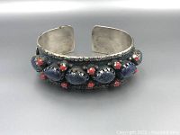 Front angle showing lapis lazuli stones and coral bead accents on the wide silver cuff bracelet.