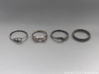 All four sterling silver rings together displayed in a row on a neutral background, showing variety in design and condition.