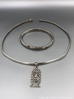 Full view of sterling silver necklace with Egyptian scarab pendant and matching sterling silver bangle bracelet laid out on display.