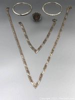 Top view of entire sterling silver vintage jewelry set including necklace, bracelet, earrings, and ring on gray background