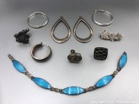 All items shown including enamel bracelet, assorted earrings and brooches arranged on plain surface.