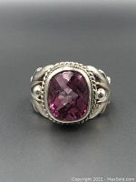Close-up front view of sterling silver ring with large faceted pink gemstone and decorative silver setting.