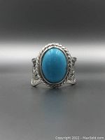 Front close-up of the sterling silver ring with deep blue oval turquoise stone and twisted rope bezel.