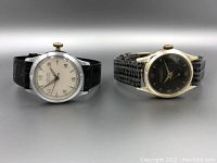 Two vintage mechanical wristwatches side by side, one with white dial and silver tone case by Gruen, the other with black dial and gold tone case.