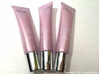 Front view of three pink tubes of Orlane Paris Firming Serum for neck and décolleté with silver caps.