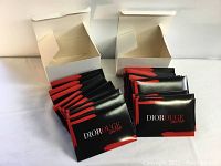 Two white boxes open with black and red Christian Dior Ultra Rouge lipstick sample packs inside, spread out to show quantity and packaging.
