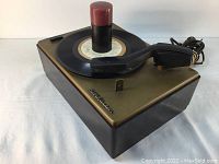 Side view of RCA Victor Victrola phonograph with record and tonearm, showing Bakelite case and power cord.