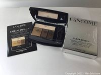 Closed and open Lancôme Color Design Eye Brightening palette with packaging and instruction leaflet showing the palette shades and layout.