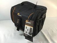 Black and orange Lowepro Adventura SH 160 II camera bag with front buckle and attached product tag.