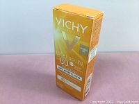 Front angle photo of Vichy Laboratories Ideal Soleil sunscreen lotion box, yellow-orange gradient, SPF 60, 45ml, showing detailed front text stating 100% mineral filter with titanium dioxide and broad spectrum protection.