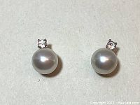 Front view of Swarovski Tricia earrings showing white Swarovski crystals above round white pearls on rhodium plated setting.