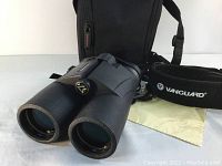 Front view of Vanguard Venture binoculars with lenses, placed near carrying case, neck strap, and lens cloth.