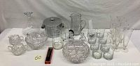 Wide view of the entire set showing all glassware including ice bucket, pitchers, various glasses, bowls, and stir sticks.