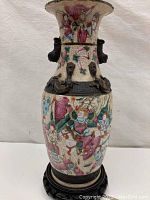 Front view of Chinese porcelain vase on wood stand showing crackle glaze and famille rose enamel decoration
