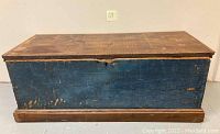 Front view of the blue wooden chest showing worn paint and large rectangular shape.