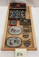 Overview of lot items displayed on a wooden tray showing multiple small decorated boxes, brass buckles, two cloisonné dishes, and the tin box.