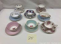 Seven collectible fine bone china tea cups with matching saucers featuring various floral and decorative patterns.