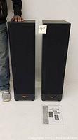 Pair of black Klipsch floorstanding speakers side by side with grille covers on