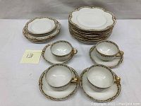 Four teacups with four matching saucers, six bread plates, six salad plates set on white surface with lot number note