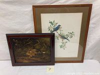 Two framed bird artworks displayed together showing the oil painting of ducks and lithograph of blue birds.