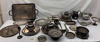 Lot of silverplate holloware and flatware including trays, bowls, teapots, and serving pieces, all tarnished and showing signs of age and use