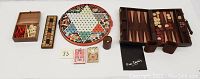 Full display of all items in the lot including the Chinese Checkers board, cribbage board, backgammon board with pieces, chess pieces, and two decks of playing cards.