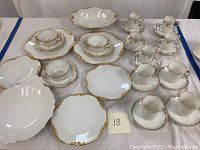 Full view of partial set of demitasse cups, saucers, small plates, and serving bowl arranged on table.