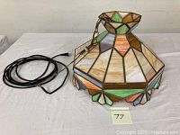 Full view of the stained glass hanging lamp shade with attached chain and cord showing colors and overall shape.