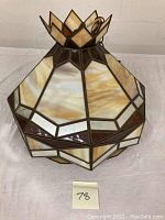 Overall view of the vintage stained slag glass hanging shade showing the geometric glass panels in amber, cream, and white and its approximately 14.5 x 18.5 inch dimensions.