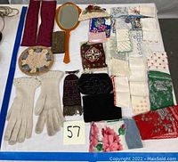 Overview of the lot showing gloves, handkerchiefs, coin purses, and vanity mirror.