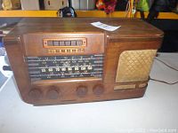 Front view of wooden cabinet radio showing tuning dial, push buttons and speaker grille