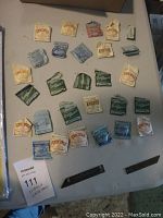 Array of sealed vintage watch crystal packets from various brands and sizes laid out on a surface.